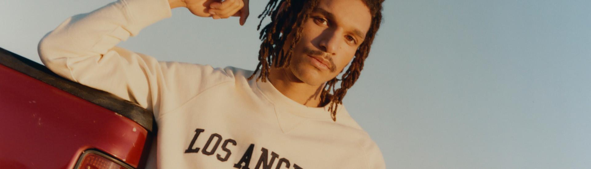 Image of man wearing cream sweatshirt with Los Angeles text