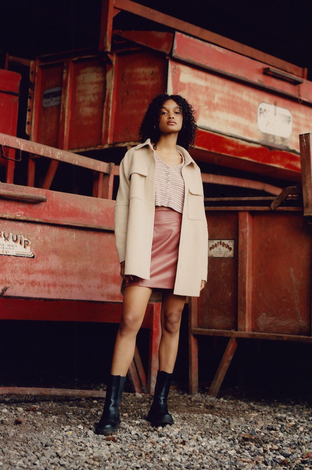 Model wearing beige shacket, pink mini skirt and cardigan