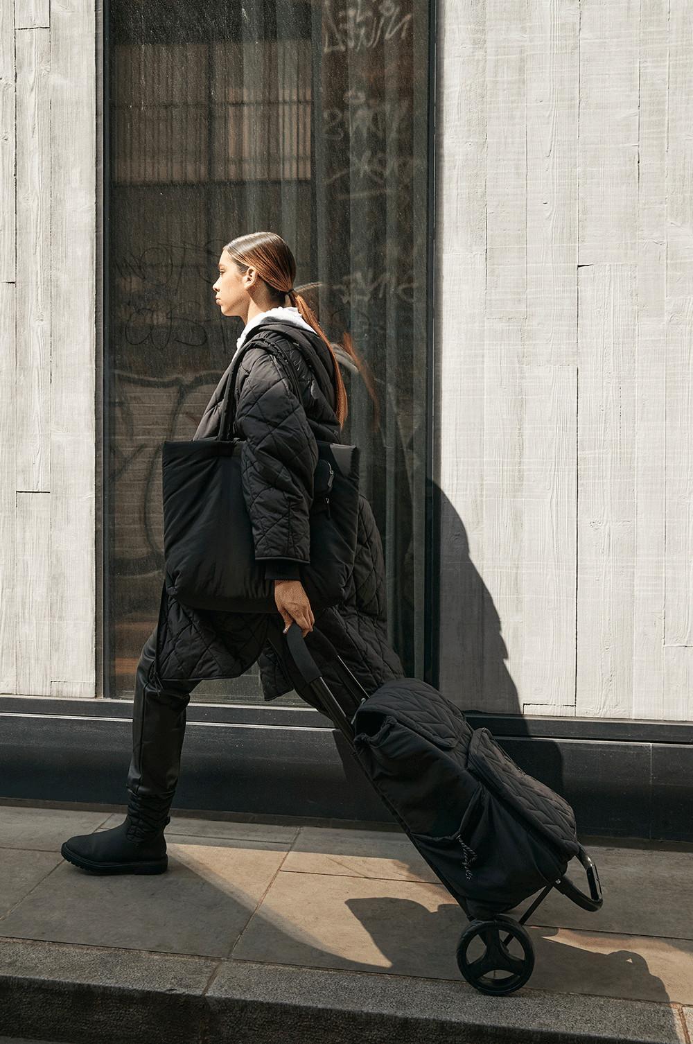 Model mit schwarzen, gesteppten Stiefeln und schwarzer, gesteppter Tasche