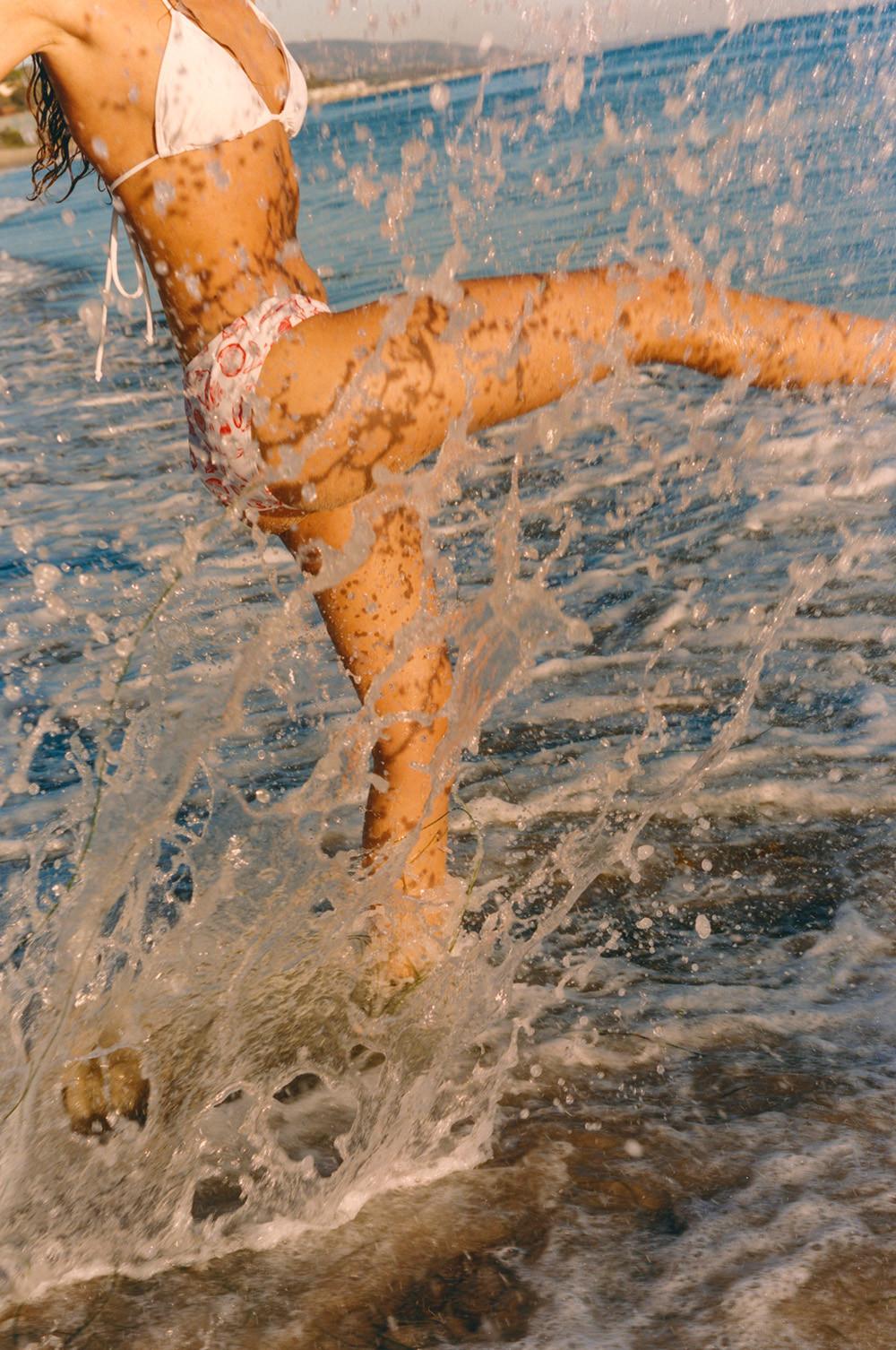 Model wears white bikini and splashes in water