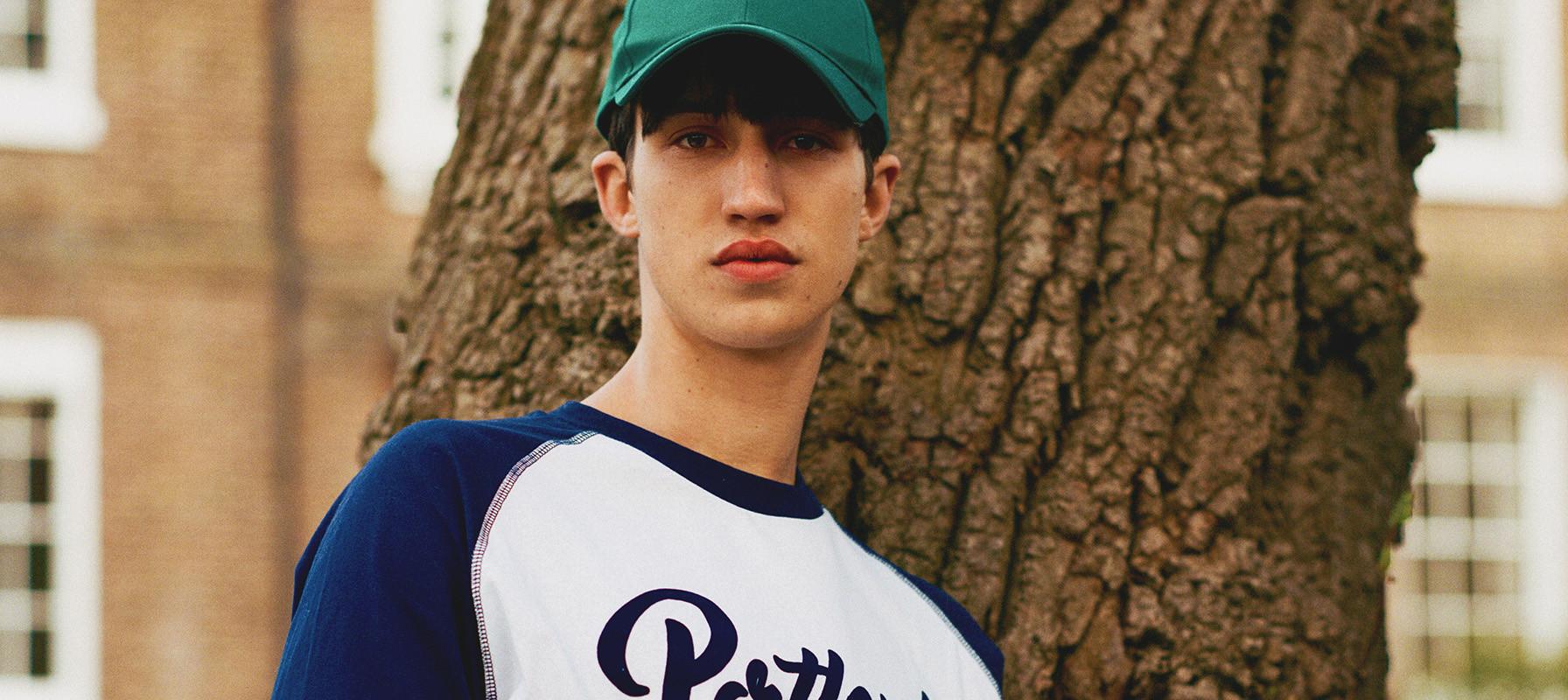 Man wearing a green cap and navy and white ringer tee