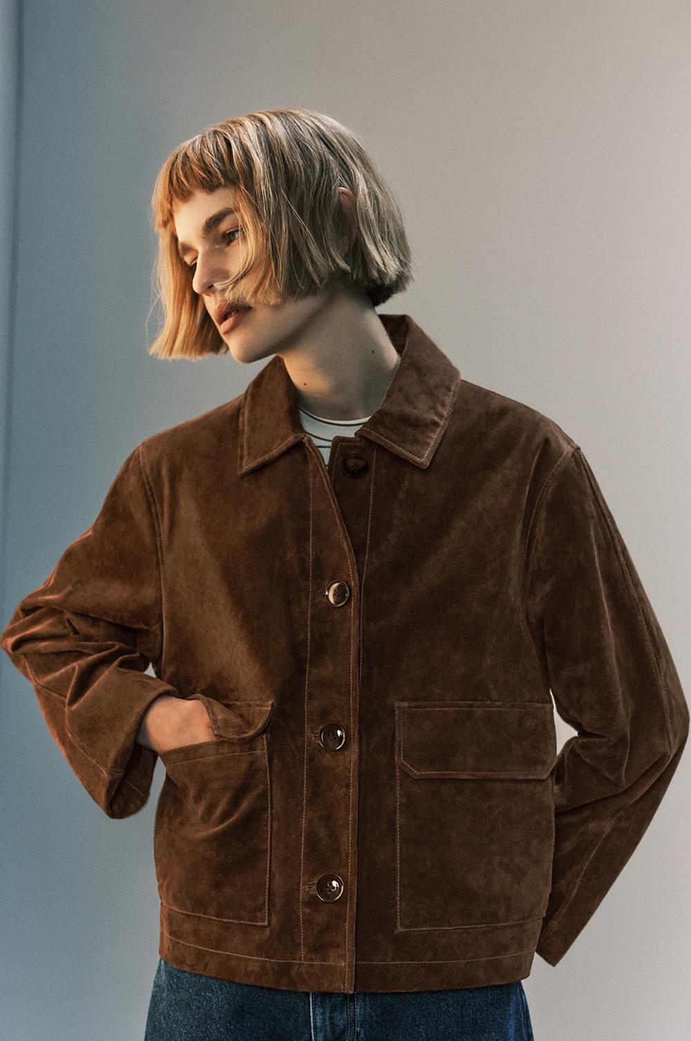Modelo con un corte de pelo bob y chaqueta de terciopelo marrón con botones sobre una camiseta a rayas.