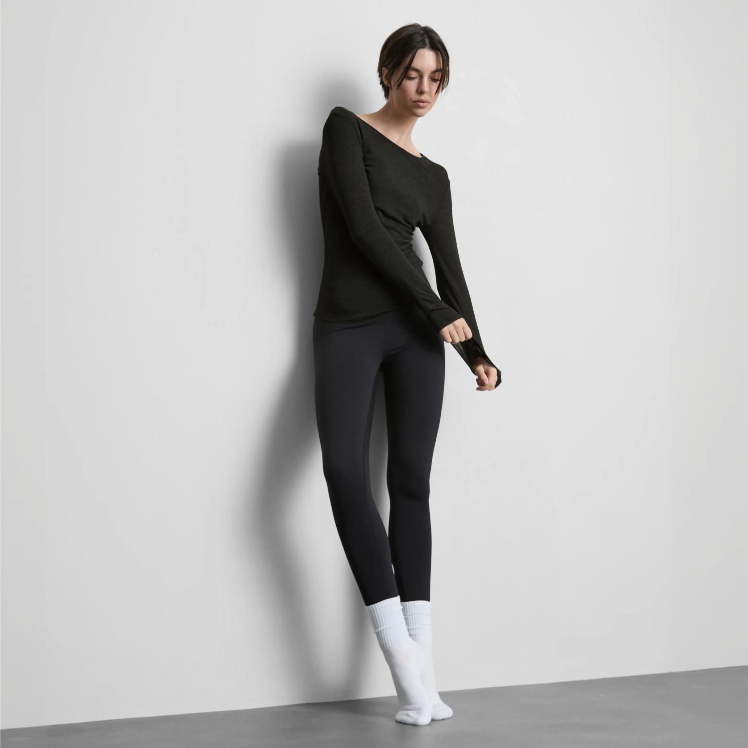 Person wearing black long-sleeve top with thumb holes and black leggings paired with white socks.
