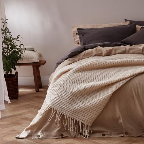 Schlafzimmer mit neutralen Bettlaken und Decke