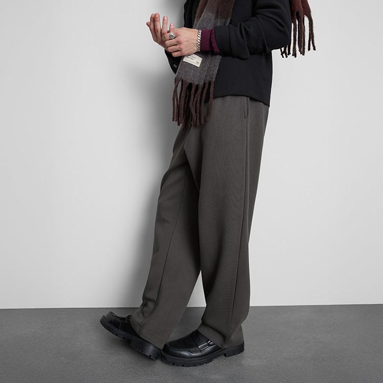 Person wearing grey wide-leg trousers with black blazer, burgundy scarf and chunky black loafers.