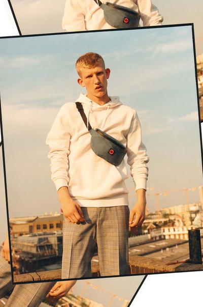 Modelo com uma camisola creme, calças em xadrez e bolsa de cintura