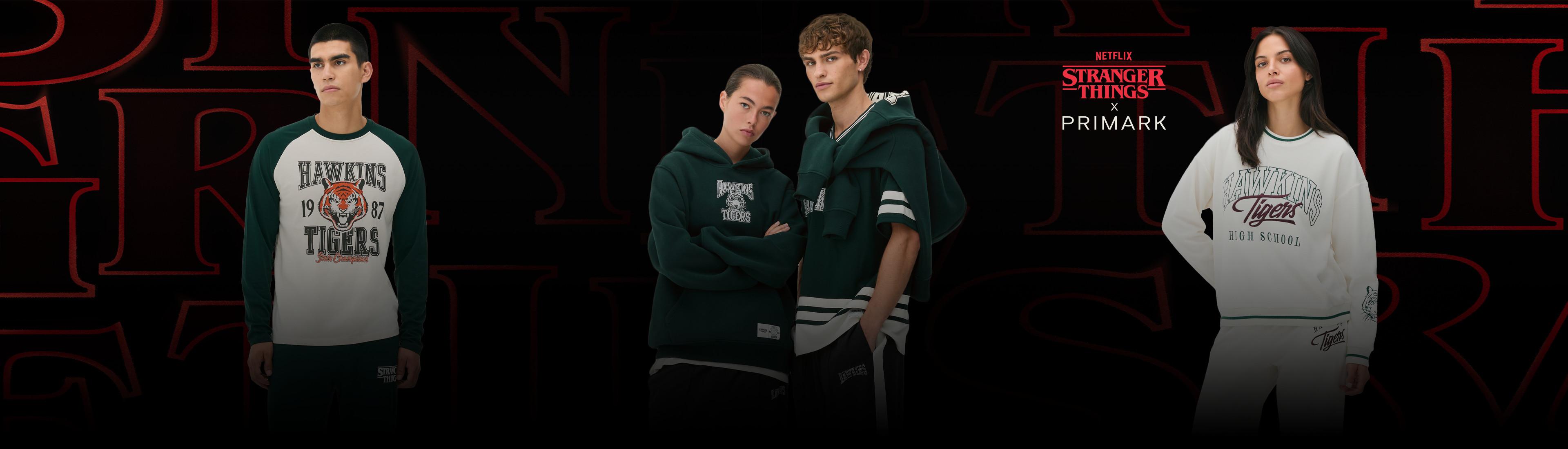 Groupe de mannequins portant la collection Stranger Things x Primark, avec vêtements Hawkins Tigers en vert et blanc.
