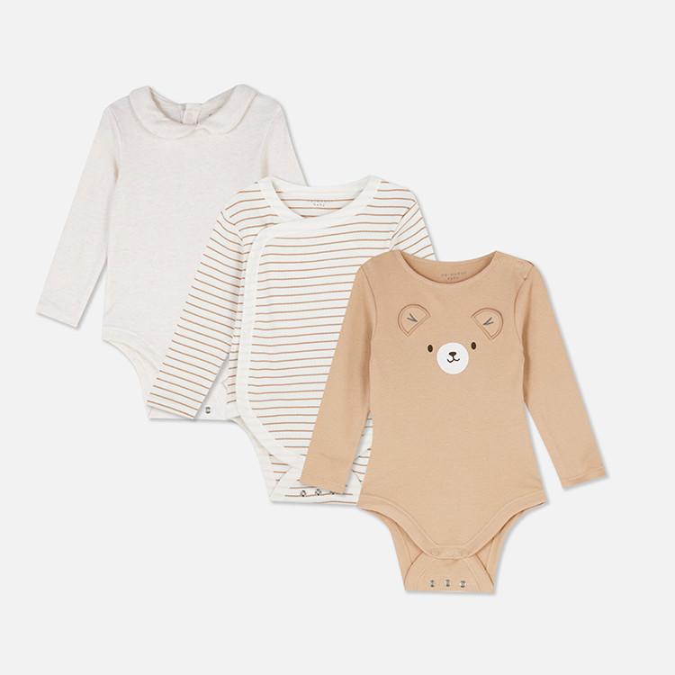 Three baby bodysuits in neutral tones: plain cream with Peter Pan collar, striped white and tan, and tan with bear face design.