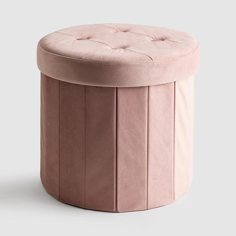 Round pink velvet storage ottoman with tufted cushion top and vertical pleated sides.