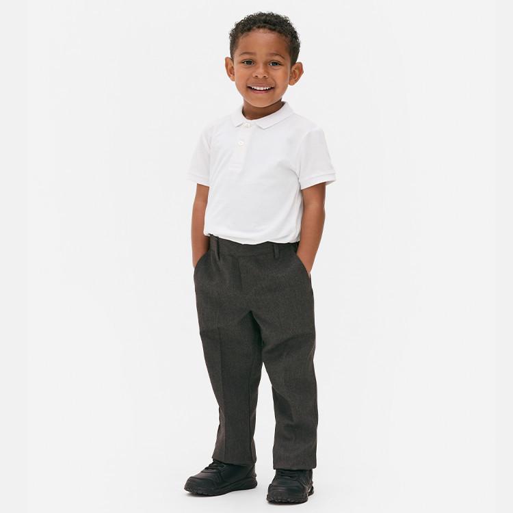 Young child wearing white polo shirt with grey school trousers and black shoes.